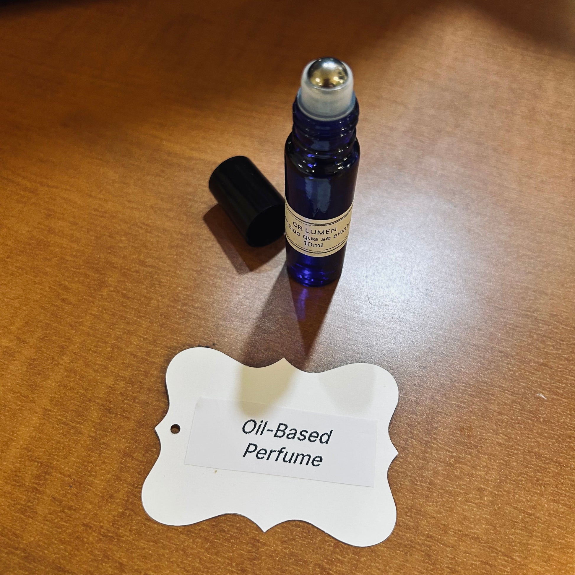 Blue rollerball bottle of oil-based perfume on a wooden surface with a label.