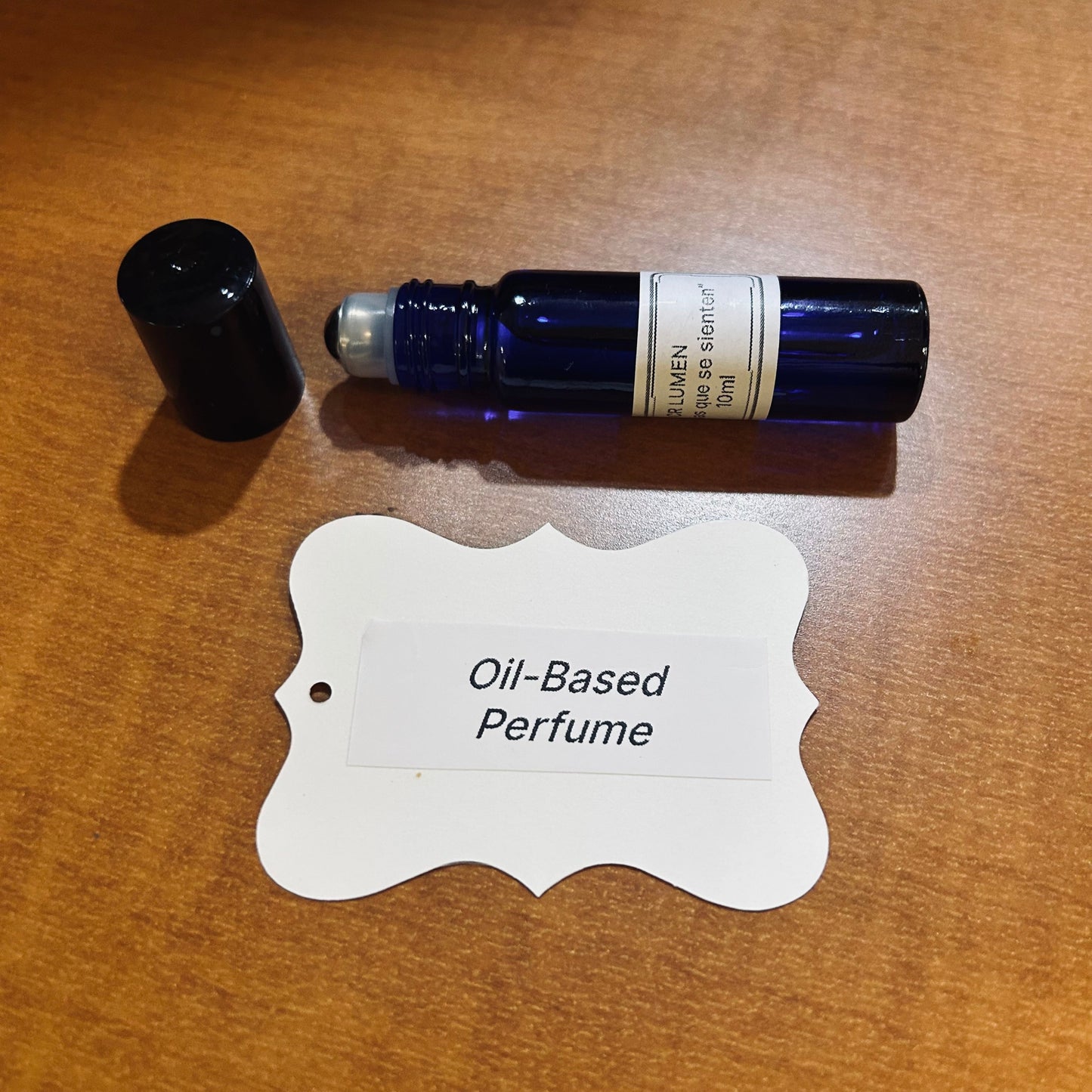 Blue rollerball bottle of oil-based perfume on a wooden surface with a label.