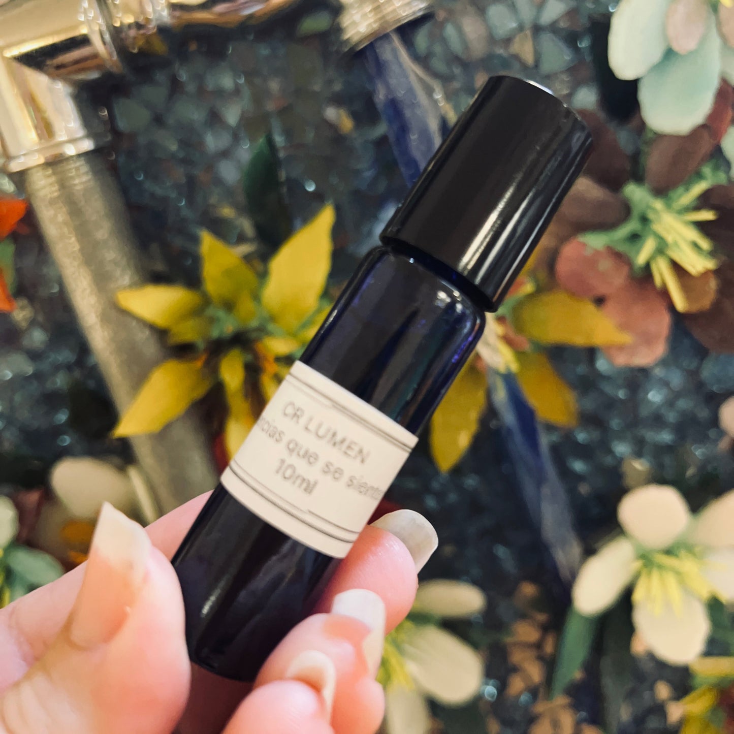 Small black bottle with a label held by a hand against a decorative background